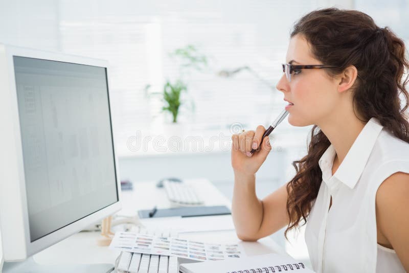 Focused businesswoman with glasses using computer in the office. Computer editing stock images, royalty-free photos and pictures