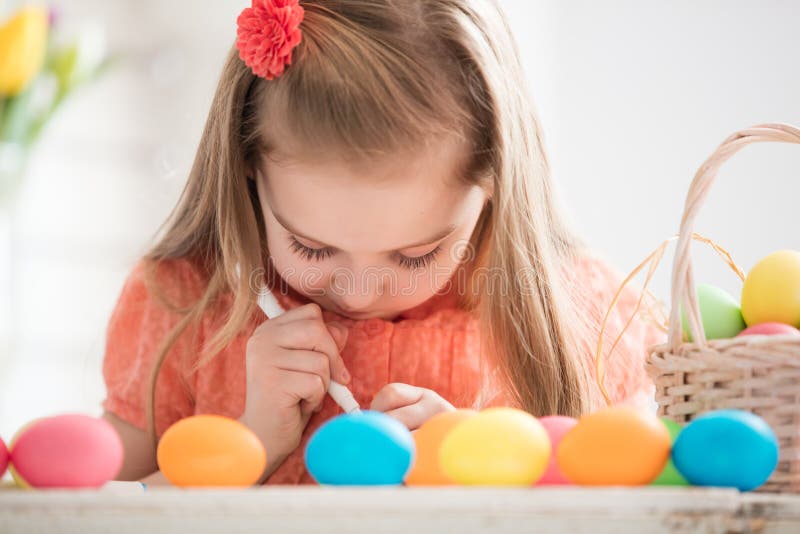 Focused child creating drawings on colorful dyed eggs stock photo
