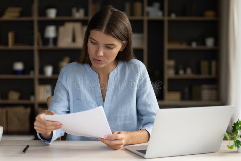 Focused female employee reading document, report, contract text