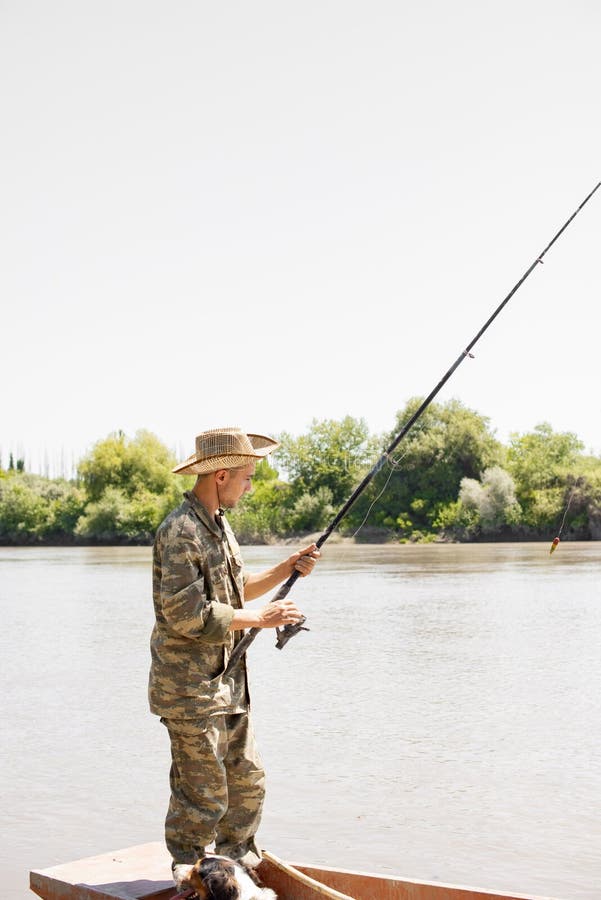 Focused Male Fisher in Camo Outfit Fishing, while Standing at