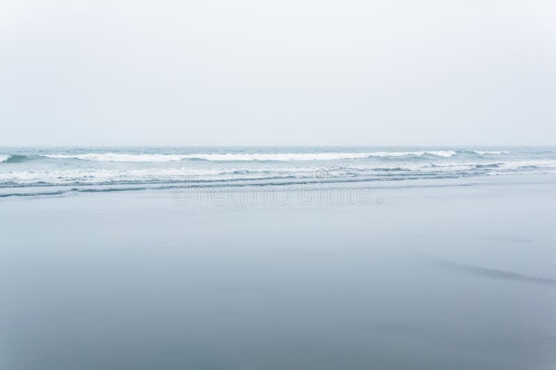 Foggy seascape, cold ocean shore with a wide beach royalty free stock images