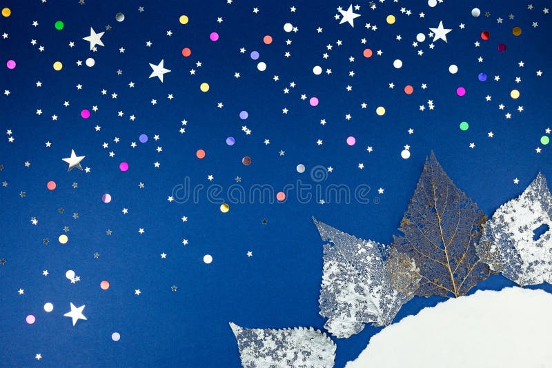 Foglie d'argento asciutte, coriandoli variopinti su carta blu fotografie stock Foglie d'argento asciutte, coriandoli variopinti su carta blu fotografie stock