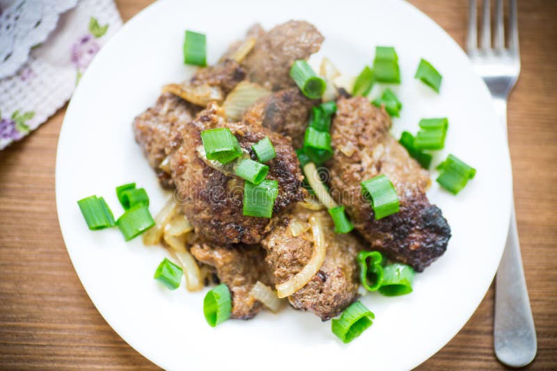 Foie frit aux oignons dans un plat sur un en bois image stock Foie frit aux oignons dans un plat sur un en bois image stock