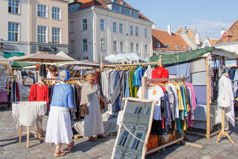 Foire sur la place d'hôtel de ville de Tallinn Dame âgée choisissant une robe photographie stock libre de droits Foire sur la place d'hôtel de ville de Tallinn Dame âgée choisissant une robe photographie stock libre de droits