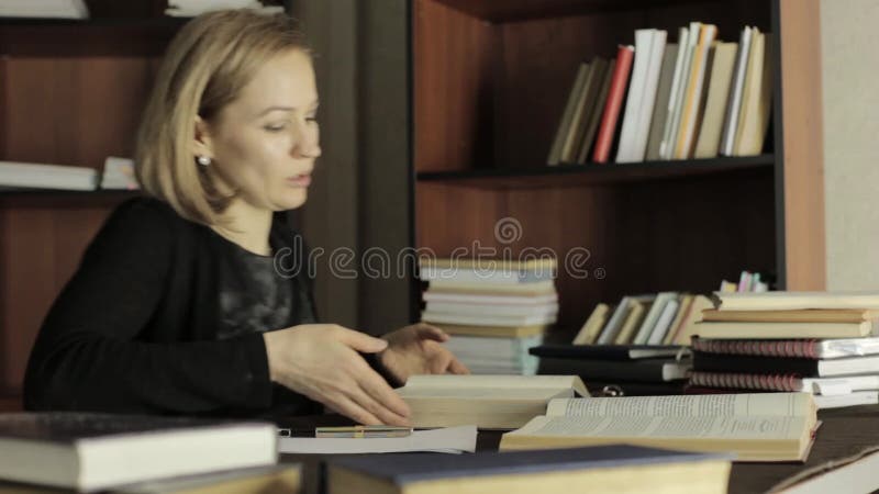Fokussierte Studentin, die mit Büchern in einer Bibliothek in der Universität arbeitet Müder Student, der für Prüfungen sich vorb