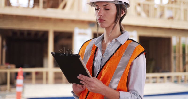 Fokussierte weibliche Bauarbeiterin auf Padper-Gerät durch unfertiges Bauen