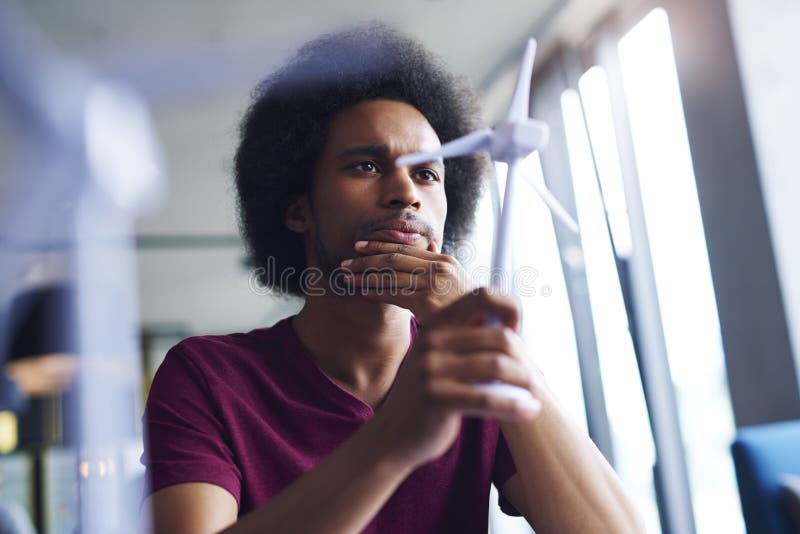 Fokussierter afrikanischer Mann, der Modell der Windkraftanlage betrachtet stockbilder Fokussierter afrikanischer Mann, der Modell der Windkraftanlage betrachtet stockbilder