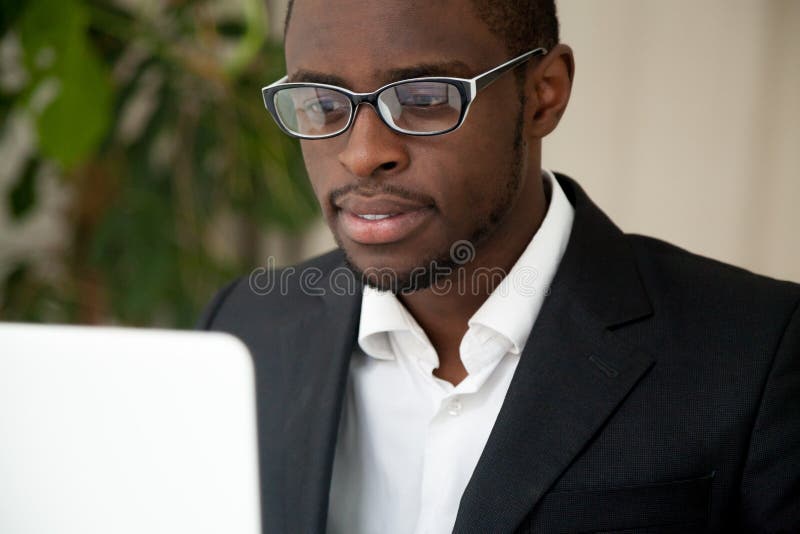 Fokussierter Afroamerikaner CEO, der den Laptopschirm liest Ne betrachtet lizenzfreies stockfoto Fokussierter Afroamerikaner CEO, der den Laptopschirm liest Ne betrachtet lizenzfreies stockfoto