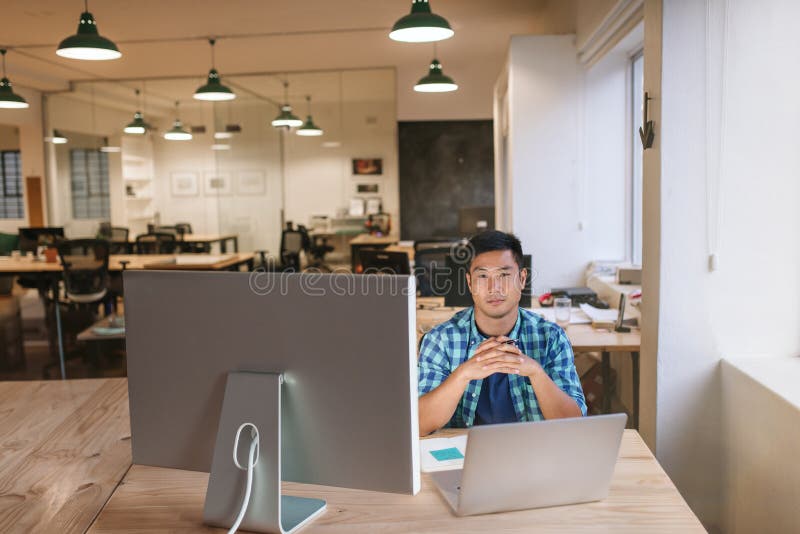 Fokussierter junger Designer, der an seinem Arbeitsplatz in einem Büro sitzt stockfoto Fokussierter junger Designer, der an seinem Arbeitsplatz in einem Büro sitzt stockfoto