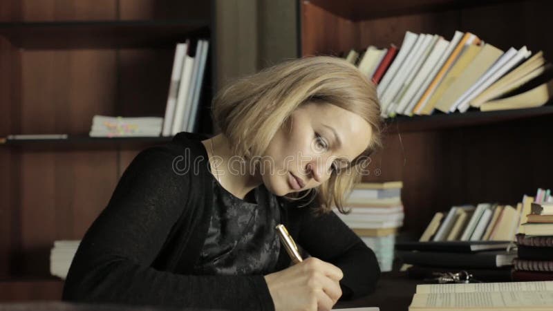 Fokussierter Student, der in der Bibliothek im College studiert Studentin, die am Schreibtisch sitzt und Hausarbeit tut