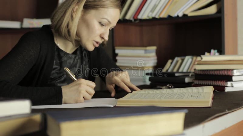Fokussierter Student, der in der Bibliothek im College studiert Studentin, die am Schreibtisch sitzt und Hausarbeit tut