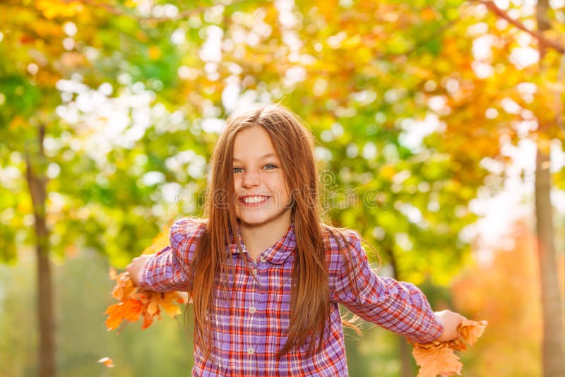 Folhas de bordo felizes do lance da menina no ar foto de stock royalty free Folhas de bordo felizes do lance da menina no ar foto de stock royalty free