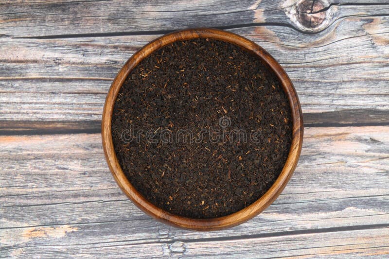 Folhas de chá preto seco isoladas sobre fundo de madeira.