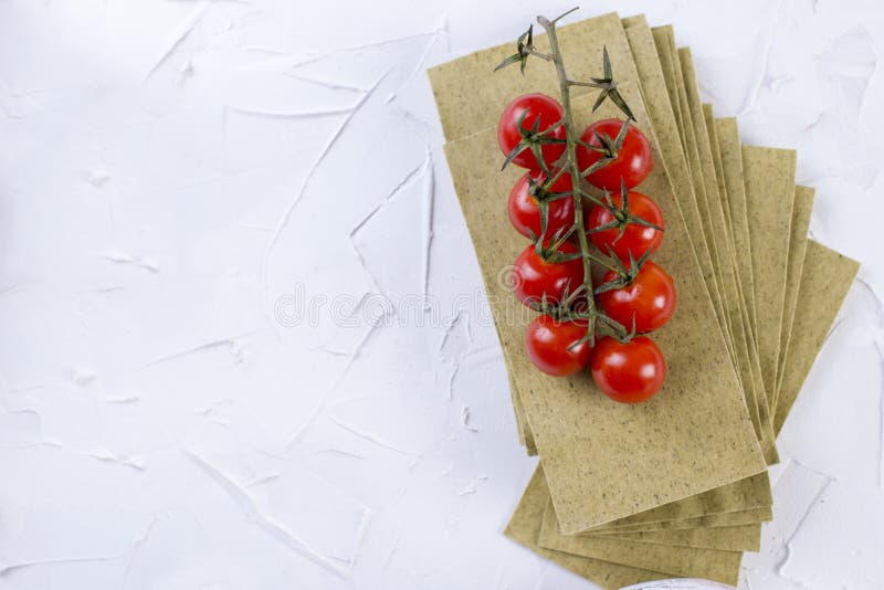 Folhas de tomates das lasanhas e de cereja, em um fundo concreto branco imagem de stock Folhas de tomates das lasanhas e de cereja, em um fundo concreto branco imagem de stock