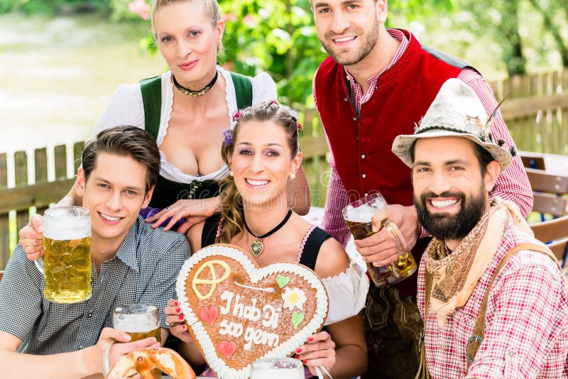 Folk med pepparkakahjärta i ölträdgård royaltyfria foton Folk med pepparkakahjärta i ölträdgård royaltyfria foton