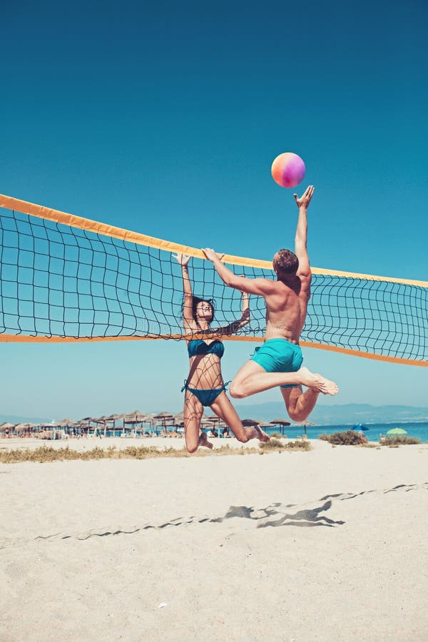 Folk som spelar strandvolleyboll som har gyckel i sportig aktiv livsstil Man som slår salvabollen i lek i sommar Kvinna royaltyfria foton Folk som spelar strandvolleyboll som har gyckel i sportig aktiv livsstil Man som slår salvabollen i lek i sommar Kvinna royaltyfria foton