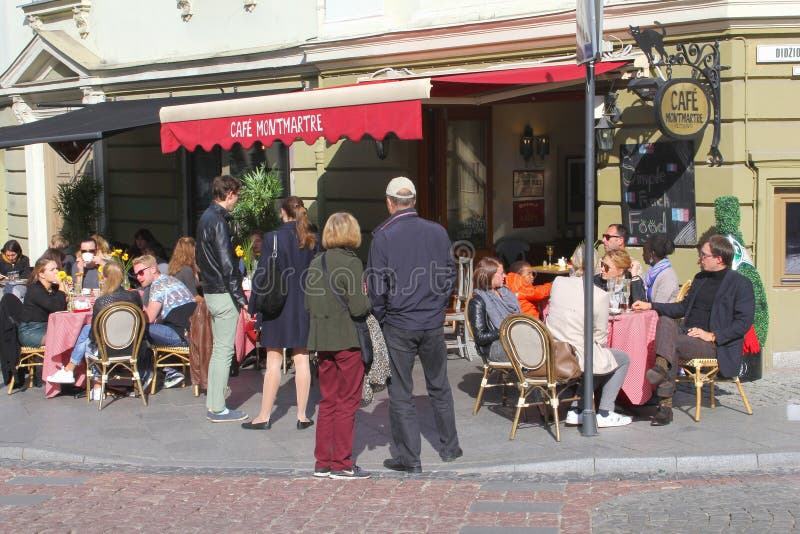 Folket tycker om och kopplar av på en solig kaféterrass i den gamla staden av Vilnius, Litauen royaltyfri fotografi Folket tycker om och kopplar av på en solig kaféterrass i den gamla staden av Vilnius, Litauen royaltyfri fotografi