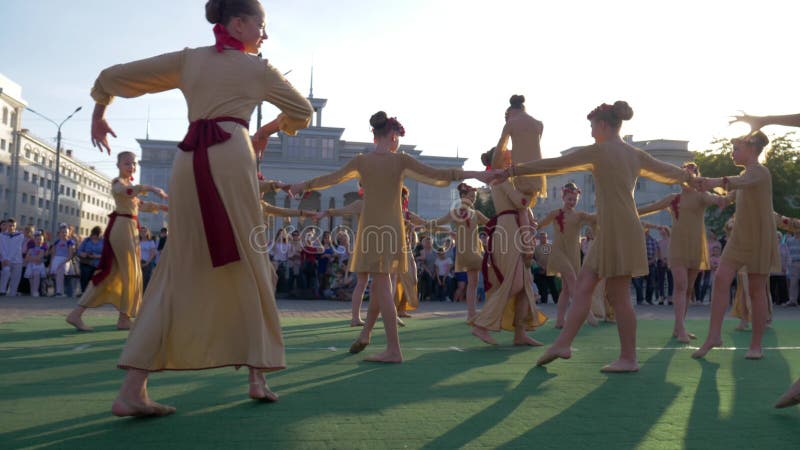 Folklore-Festival, Gruppe junge Frauen in den Nationalitätskostümen, die in Stadtplatz vor Mengenleuten am Feiertag tanzen