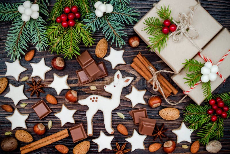 Fond de Noël avec des biscuits de pain d'épice, des présents, des branches de sapin et des épices sur le vieux conseil en bois photo stock Fond de Noël avec des biscuits de pain d'épice, des présents, des branches de sapin et des épices sur le vieux conseil en bois photo stock