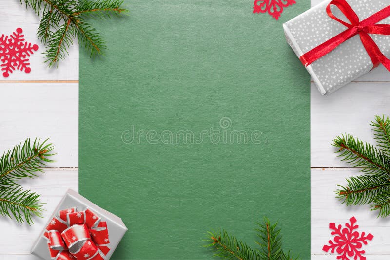 Christmas background with decorations on white wooden table and green tablecloth with free space for greeting text. Gifts, fir branches and snowflake decorations. Top view. Christmas background with decorations on white wooden table and green tablecloth with free space for greeting text. Gifts, fir branches and snowflake decorations. Top view.