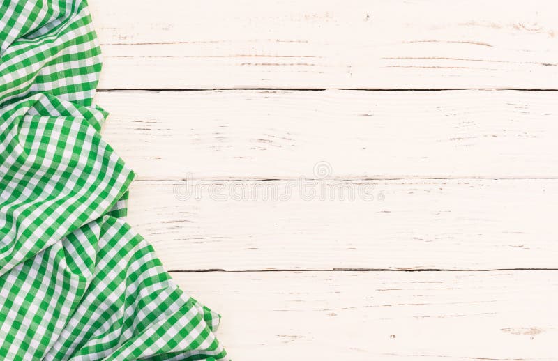 White wooden table background with rustic green checkered tablecloth on left side, high angle view. White wooden table background with rustic green checkered tablecloth on left side, high angle view