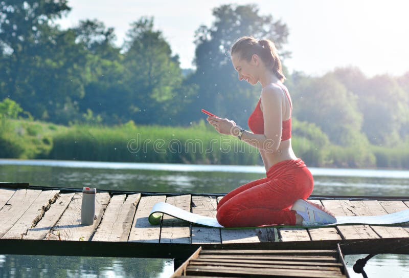 Fond sain de style de vie La fille a reçu un message agréable de sms pendant le yoga sur l'extérieur d'air frais photographie stock libre de droits Fond sain de style de vie La fille a reçu un message agréable de sms pendant le yoga sur l'extérieur d'air frais photographie stock libre de droits