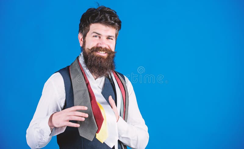 He is fond of shopping. Happy shop assistant offering wide choice of neckties for shopping. Bearded shopper choosing necktie in shopping mall. Hipster shopping the latest tie collection, copy space.