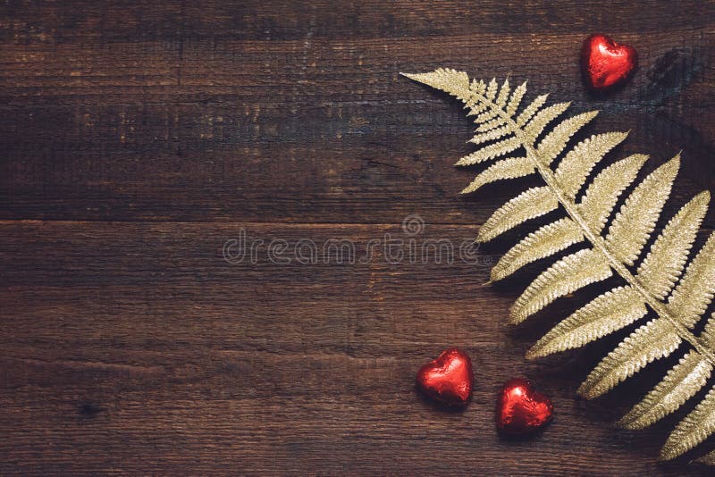 Fondo de día de San Valentín, maqueta con los caramelos de chocolate rojos de la forma del corazón y hojas de oro en fondo de mad imagen de archivo libre de regalías Fondo de día de San Valentín, maqueta con los caramelos de chocolate rojos de la forma del corazón y hojas de oro en fondo de mad imagen de archivo libre de regalías
