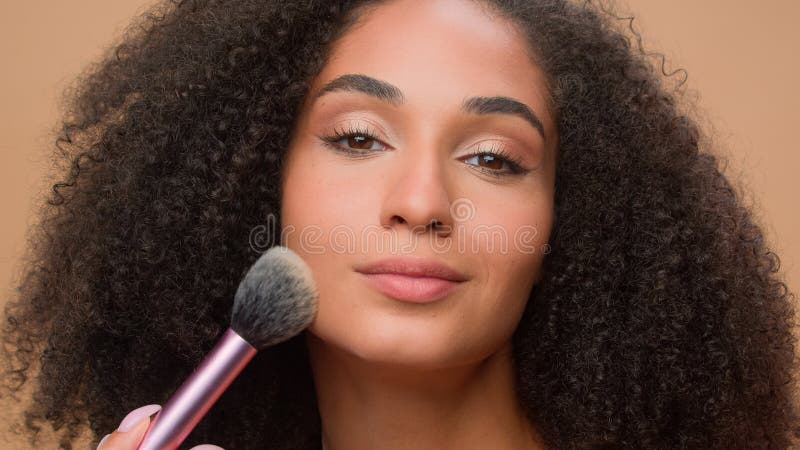 Fondo de estudio de retrato beige de cierre hermosa afroamericana con piel suave perfecta aplicar el aspecto de polvo foto de archivo