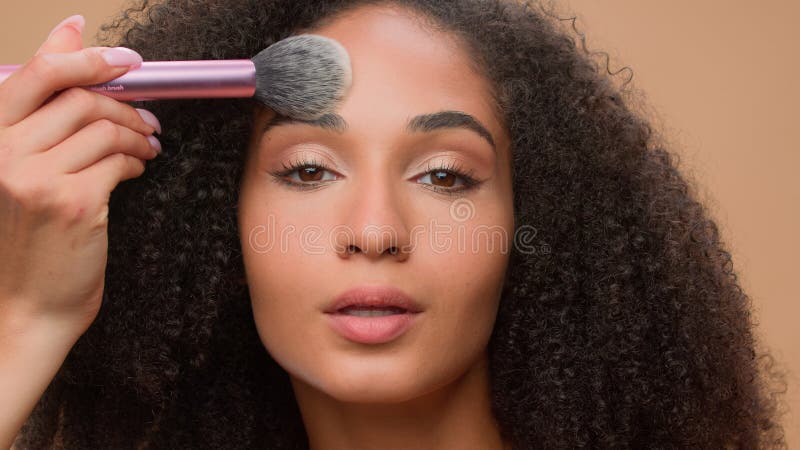 Fondo de estudio de retrato de color beige hermosa afroamericana con piel suave perfecta aplicar el aspecto del polvo imagen de archivo
