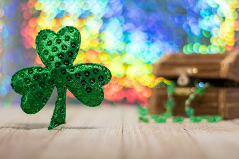 Happy St. Patrick`s Day fun rainbow background on wooden board with treasure chest and shamrock and gold coins, selective focus, shallow DOF. Happy St. Patrick`s Day fun rainbow background on wooden board with treasure chest and shamrock and gold coins, selective focus, shallow DOF