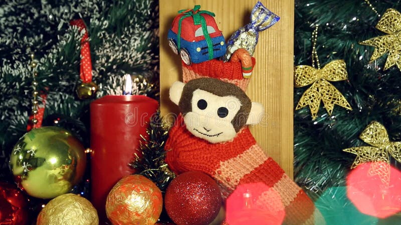 Fondo di Natale con le luci e la scimmia della candela sul calzino rosso