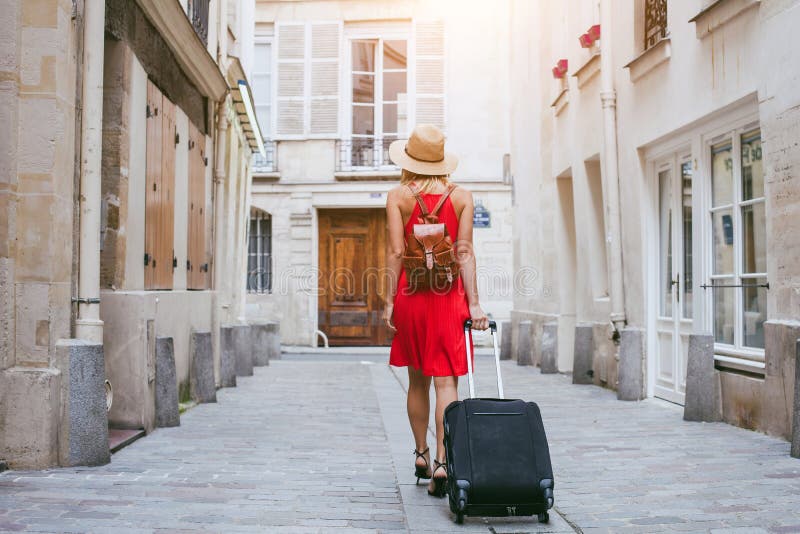 Fondo di viaggio, turista della donna che cammina con la valigia sulla via in città europea, turismo