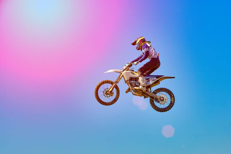 Fondo extremo de los deportes - silueta del motorista que salta en la moto en puesta del sol, contra el cielo azul imagen de archivo Fondo extremo de los deportes - silueta del motorista que salta en la moto en puesta del sol, contra el cielo azul imagen de archivo