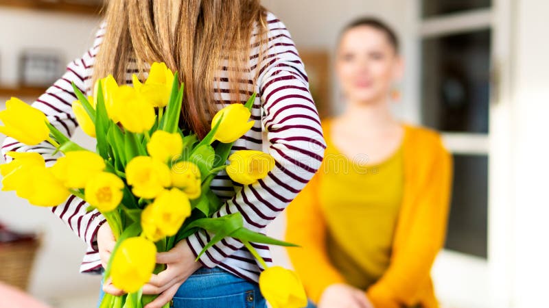 Fondo felice di compleanno o di festa della Mamma Ragazza adorabile sorprendente la sua mamma con il mazzo dei tulipani gialli fotografia stock libera da diritti Fondo felice di compleanno o di festa della Mamma Ragazza adorabile sorprendente la sua mamma con il mazzo dei tulipani gialli fotografia stock libera da diritti