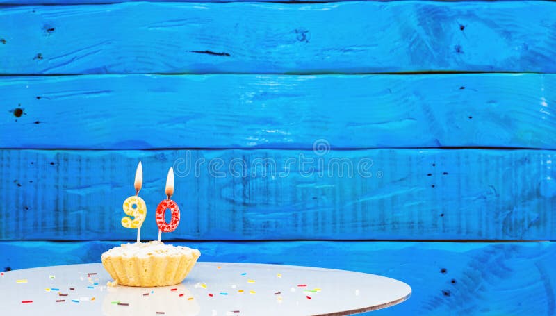 Festive background with a cake on the background of blue boards, copy space, a beautiful background for a birthday with a number a candle with a figure 90. Festive background with a cake on the background of blue boards, copy space, a beautiful background for a birthday with a number a candle with a figure 90.