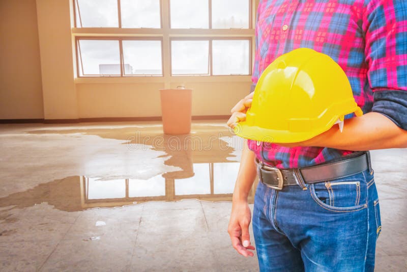 Fondo interno giallo dell'ufficio di goccia della perdita della plastica e dell'acqua del casco di sicurezza della tenuta dell'in fotografie stock Fondo interno giallo dell'ufficio di goccia della perdita della plastica e dell'acqua del casco di sicurezza della tenuta dell'in fotografie stock