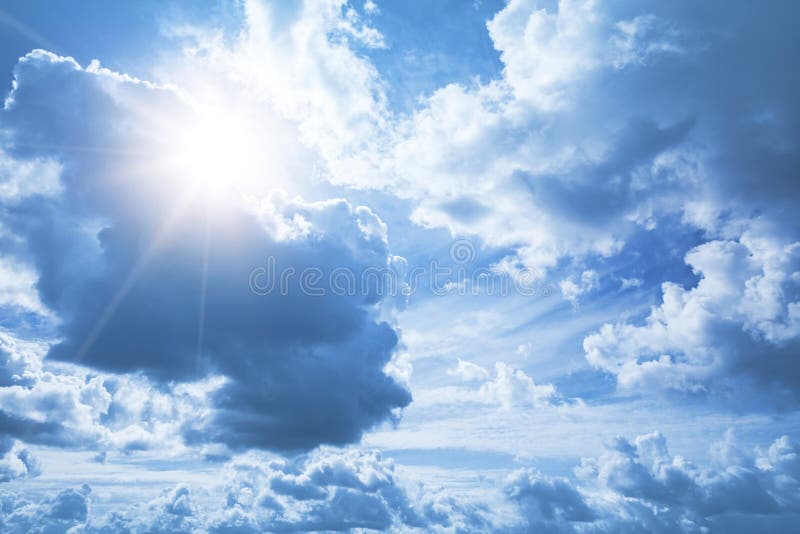 Fondo luminoso del cielo blu con le nuvole ed il sole bianchi