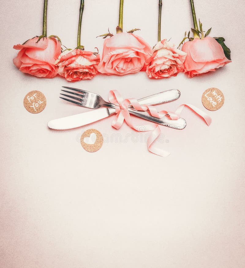 Romantic dinner background with table place setting : roses border , cutlery and ribbon on pastel background, top view, place for text. Romantic dinner background with table place setting : roses border , cutlery and ribbon on pastel background, top view, place for text