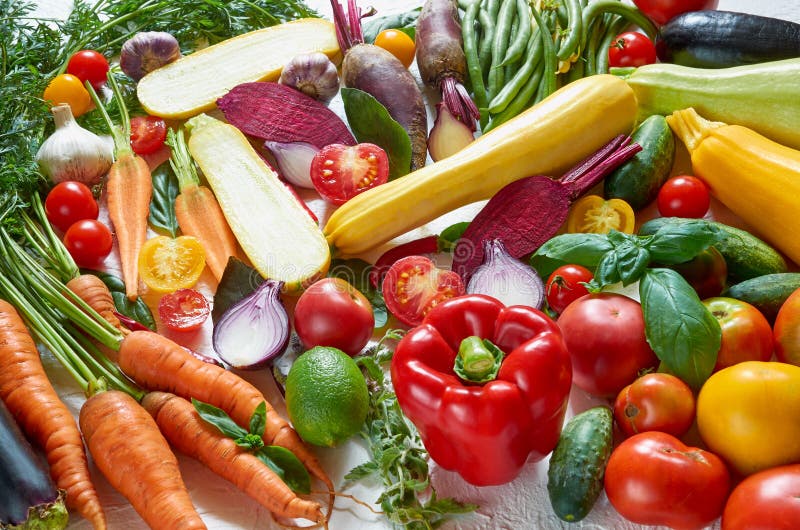 Fondo vegetariano sano dell'alimento di dieta Varie verdure organiche fresche sulla tavola bianca: pomodori, zucchini affettato