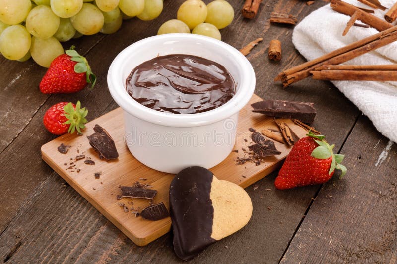 Chocolate fondue with grapes in a setting with strawberry, biscuits, grapes and cinnamon. Chocolate fondue with grapes in a setting with strawberry, biscuits, grapes and cinnamon