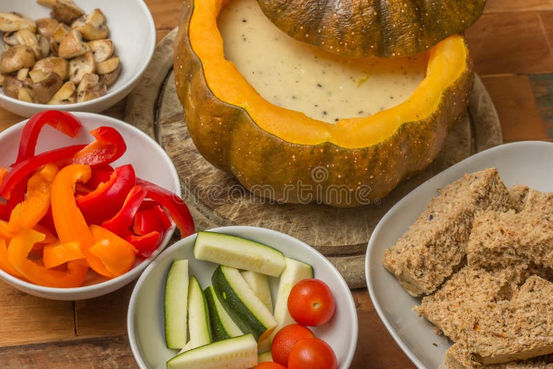 Fondue de queijo em uma abóbora roasted com pão e vegetais fotografia de stock Fondue de queijo em uma abóbora roasted com pão e vegetais fotografia de stock