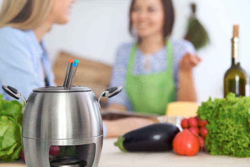 Fondue w garnku przy tłem przyjaciele gotuje wpólnie, zakończenie Kuchenni wnętrza i cookware zdjęcie royalty free Fondue w garnku przy tłem przyjaciele gotuje wpólnie, zakończenie Kuchenni wnętrza i cookware zdjęcie royalty free