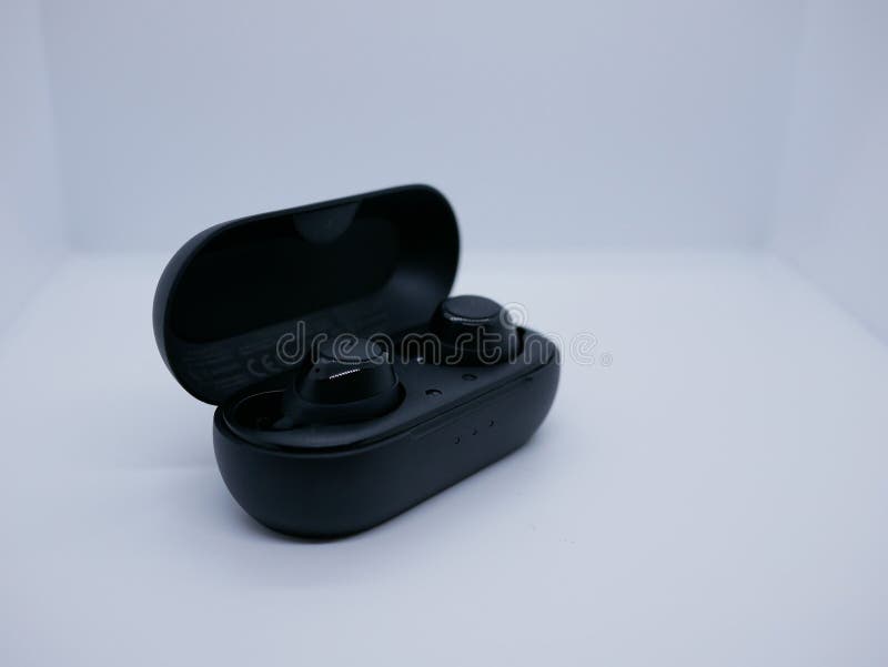 Fones de ouvido bluetooth sem fio preto moderno em um gabinete de carregamento em um fundo branco. tecnologia digital fotografia de stock