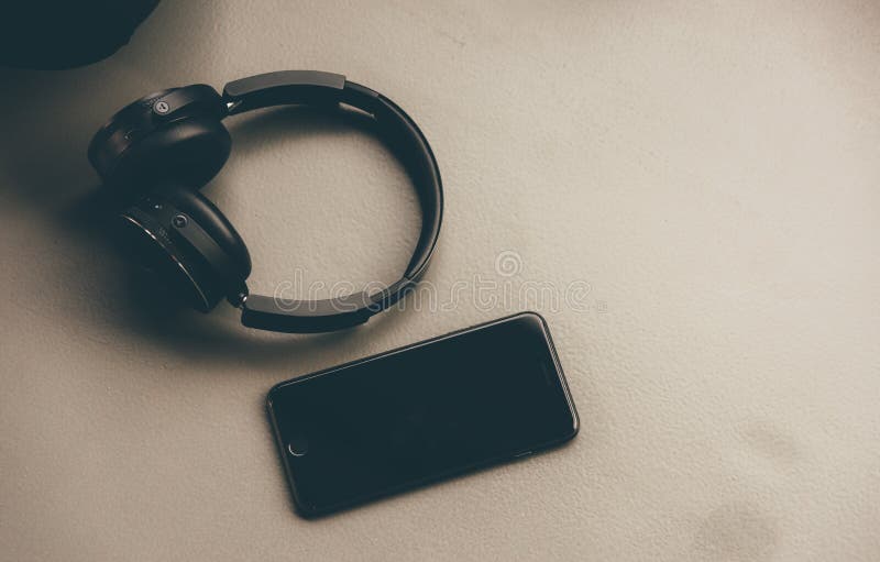 Fones de ouvido da música e telefone esperto no assoalho de borracha foto de stock Fones de ouvido da música e telefone esperto no assoalho de borracha foto de stock