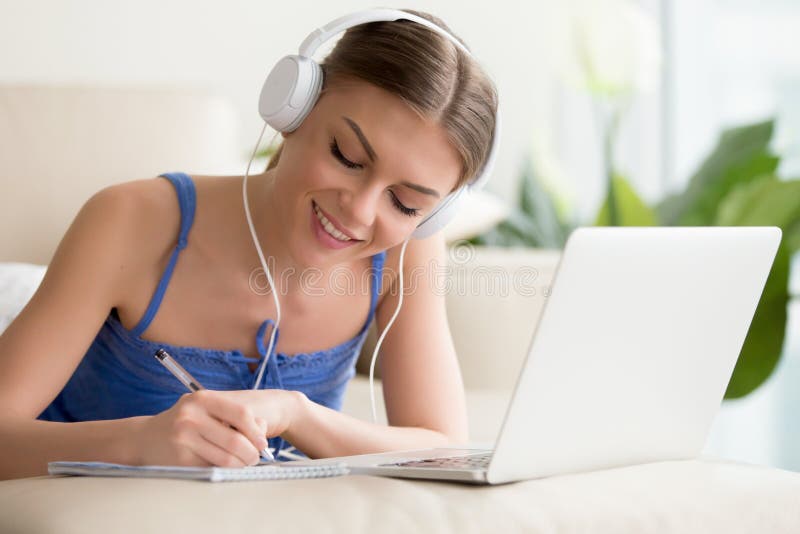 Fones de ouvido vestindo da menina que escutam o curso audio, aprendendo na frente fotos de stock royalty free Fones de ouvido vestindo da menina que escutam o curso audio, aprendendo na frente fotos de stock royalty free
