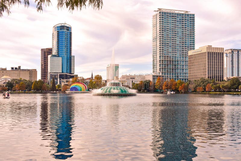 Orlando, Florida . December 24, 2018. Colorful vintage fountain , business buildings, swan boats and autumn trees at Lake Eola Park in Orlando Downtown area 1. Orlando, Florida . December 24, 2018. Colorful vintage fountain , business buildings, swan boats and autumn trees at Lake Eola Park in Orlando Downtown area 1