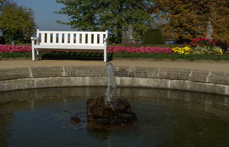 Fontaine minúsculo del agua con el banco de parque foto de archivo Fontaine minúsculo del agua con el banco de parque foto de archivo
