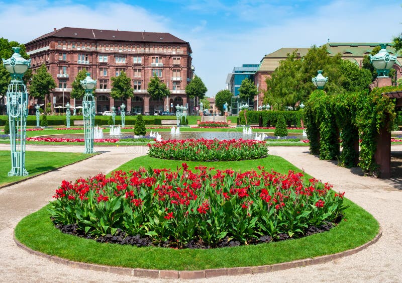 Fountain and Water Tower on Friedrichsplatz square in Mannheim - Germany. Blooming flower beds, pergolas and vintage lights on the background of the old town. Fountain and Water Tower on Friedrichsplatz square in Mannheim - Germany. Blooming flower beds, pergolas and vintage lights on the background of the old town.