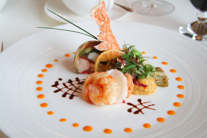 Starter or Entree of a french dish with seafood mixed among salad leaves.